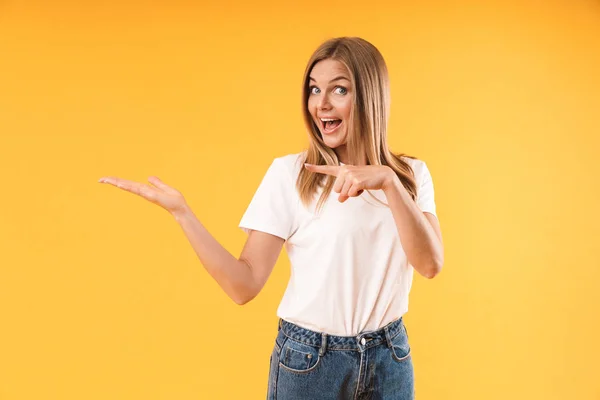 Imagem de mulher loira alegre vestindo camiseta casual sorrindo e apontando o dedo para o espaço na palma da mão — Fotografia de Stock