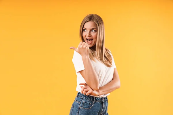 Image d'une femme blonde caucasienne portant un t-shirt décontracté souriant et pointant du doigt vers l'espace d'écriture — Photo