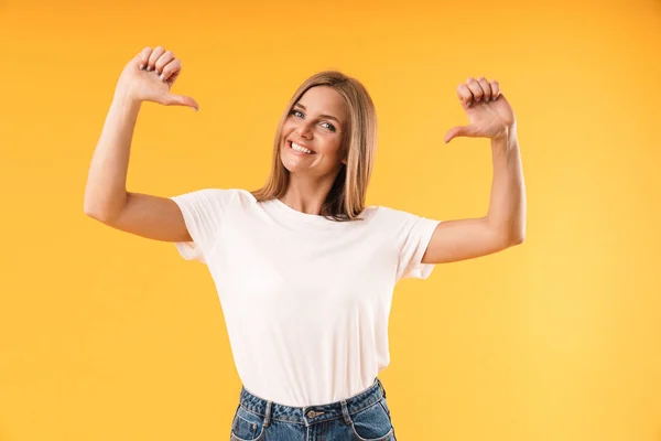 Imagen de una mujer rubia alegre vistiendo una camiseta casual sonriendo y señalándose con los dedos —  Fotos de Stock