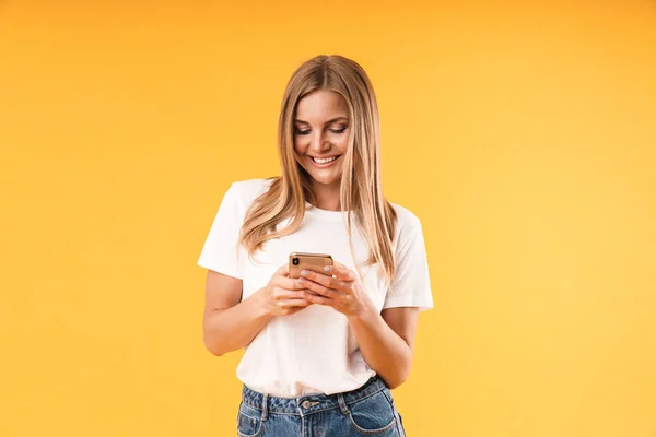 Image closeup of beautiful blond woman wearing casual t-shirt smiling while using smartphone — Stock Photo, Image