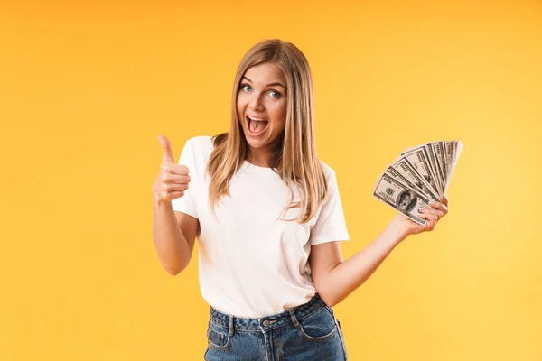 Zbliżenie obrazu kaukaski blond kobieta ubrana casual t-shirt pokazując kciuka w górę, trzymając pieniądze pieniężne — Zdjęcie stockowe