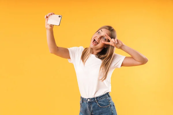 Wizerunek atrakcyjnej blond kobieta pokazując palce pokojowe podczas robienia zdjęć selfie na smartfonie — Zdjęcie stockowe