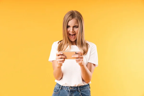 Image closeup of nervous young woman wearing casual t-shirt screaming while using smartphone — Stock Photo, Image