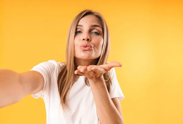 Imagen de primer plano de la mujer rubia bonita soplando aire beso en la cámara mientras toma foto selfie — Foto de Stock