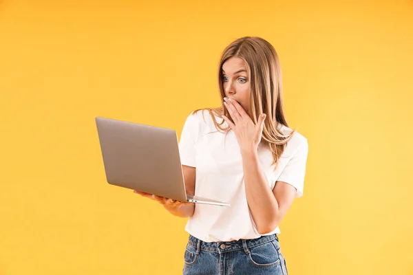 Bild av chockad blond kvinna klädd i casual t-shirt uttrycker Wonder när du använder bärbar dator — Stockfoto