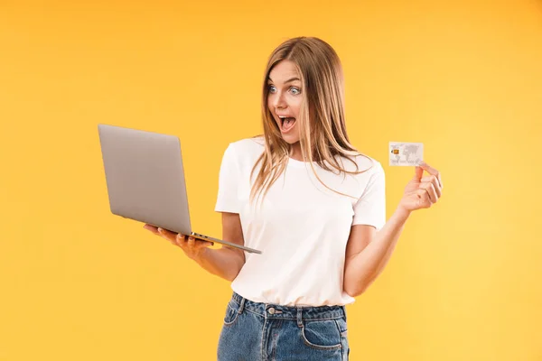 Immagine di donna bionda stupita che esprime meraviglia mentre tiene computer portatile e carta di credito — Foto Stock