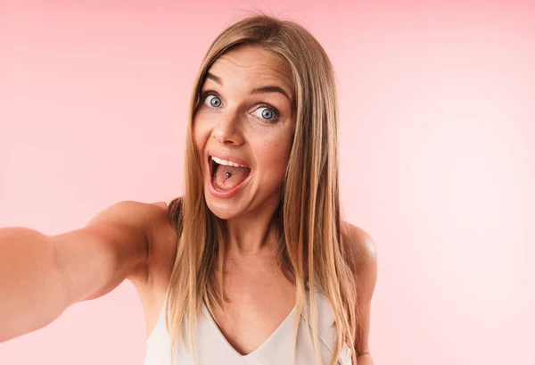 Φωτογραφία κοντινό πλάνο της έκπληκτος νεαρή γυναίκα χαμογελά στην κάμερα, ενώ παίρνετε selfie φωτογραφιών — Φωτογραφία Αρχείου