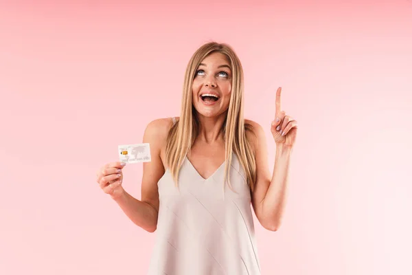 Εικόνα κοντινό στην αισιόδοξη ξανθιά γυναίκα που χαμογελά και σημαδεύει προς τα πάνω ενώ κρατά πιστωτική κάρτα — Φωτογραφία Αρχείου