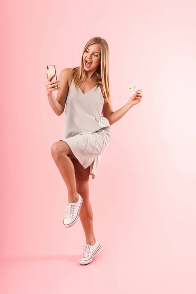 Εικόνα της ενθουσιασμένες ξανθιά γυναίκα χαμογελά ενώ κατέχουν πιστωτική κάρτα και smartphone — Φωτογραφία Αρχείου