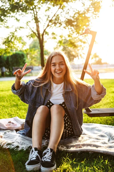 Adolescente souriante joyeuse s'asseoir sur l'herbe dans le parc naturel vert . — Photo