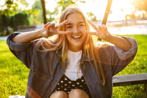 Allegro sorridente adolescente sedersi sull'erba nel parco verde della natura . — Foto Stock