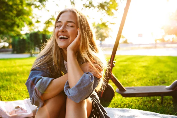 Alegre sorrindo adolescente menina sentar na grama na natureza verde parque . — Fotografia de Stock