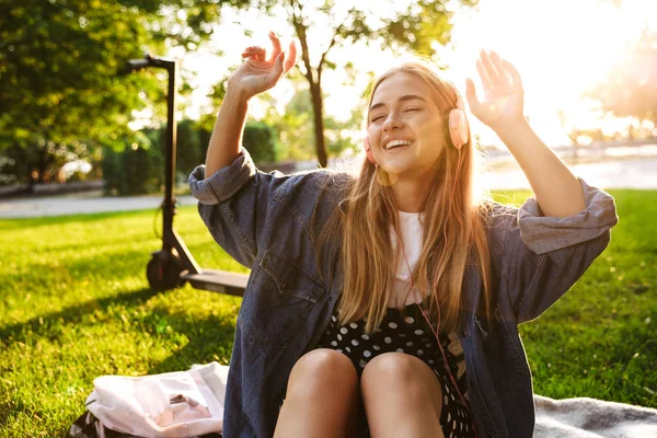 Kız dışında doğa yeşil parkta çim üzerinde kulaklık ile müzik dinleme. — Stok fotoğraf