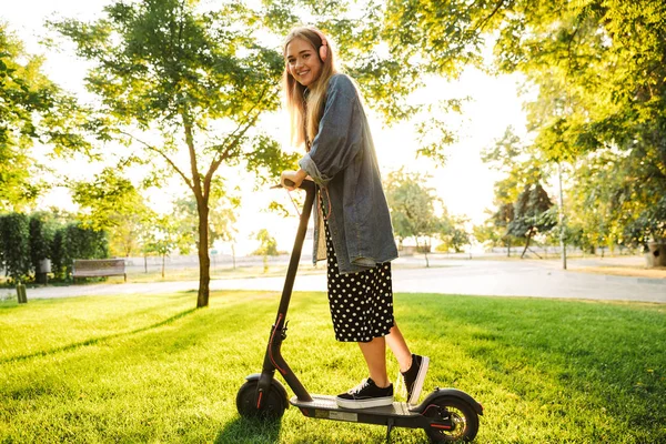 Positieve optimistische jonge tiener meisje buiten wandelen met scooter. — Stockfoto