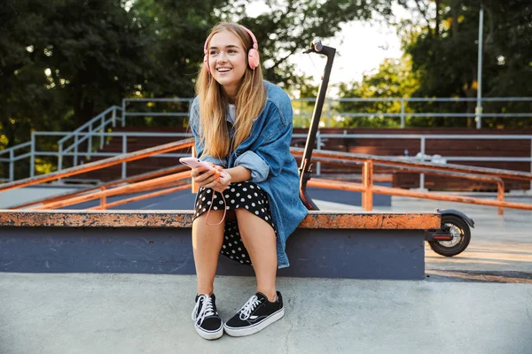 Positieve jonge tiener meisje buiten in Park houden mobiele telefoon. — Stockfoto