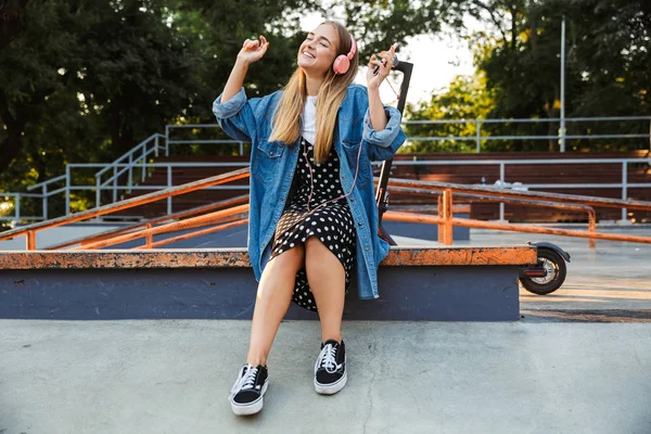 Pozitív fiatal tizenéves lány kint parkban gazdaság mobiltelefon. — Stock Fotó