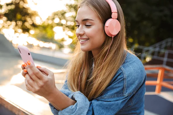 Positif jeune adolescente à l'extérieur dans le parc tenant téléphone mobile . — Photo