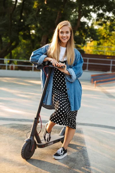 Щаслива дівчина-підліток в парку, що йде на скутері дивиться камеру . — стокове фото