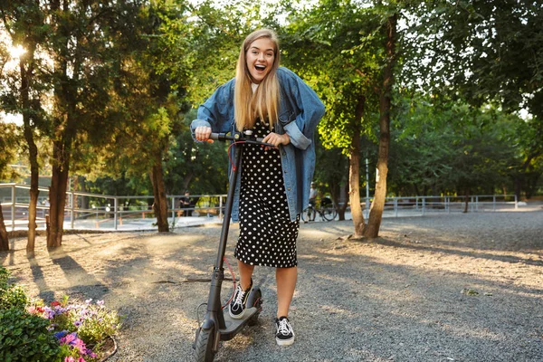 스쿠터와 함께 걷는 자연 녹색 공원에서 외부의 행복한 젊은 십대 소녀. — 스톡 사진