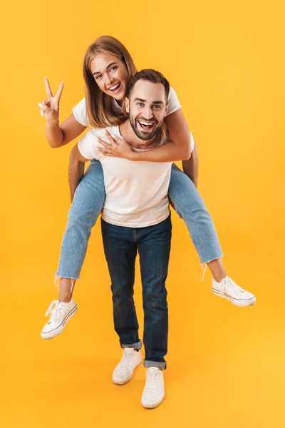 Imagem de casal sorrindo mostrando sinal de paz ao fazer passeio de piggyback — Fotografia de Stock