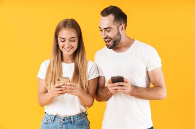 Image of cheerful man smiling while looking at cellphone of his girlfriend