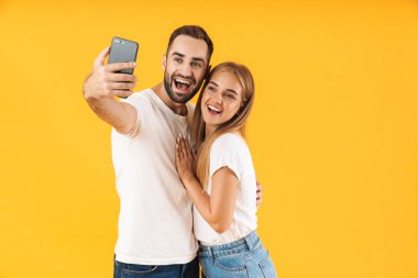 Cep telefonundan selfie fotoğrafı çekerken gülümseyen neşeli çiftin görüntüsü