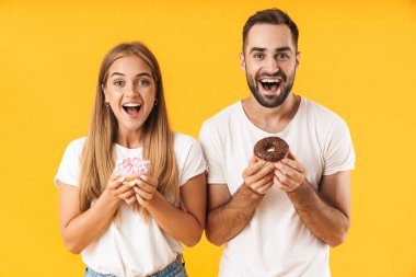 Image of excited couple smiling while holding sweet donuts together