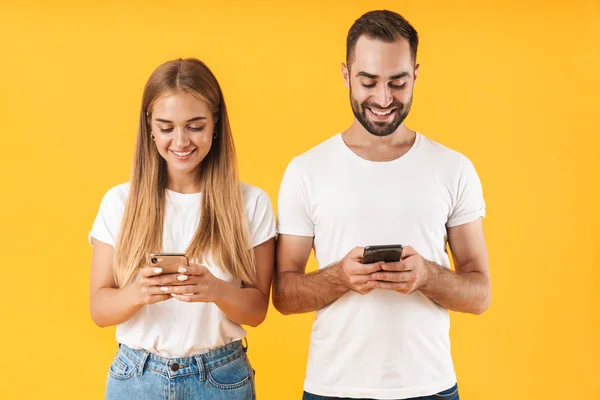 Image of positive couple ??smiling while using smartphones together — ストック写真