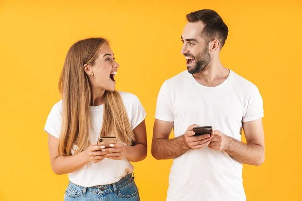 Зображення збудженої пари посміхається під час використання смартфонів разом — стокове фото