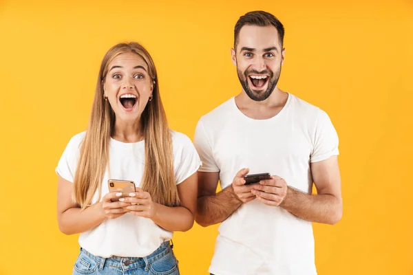 Imagen de pareja alegre sonriendo mientras usan teléfonos inteligentes juntos —  Fotos de Stock