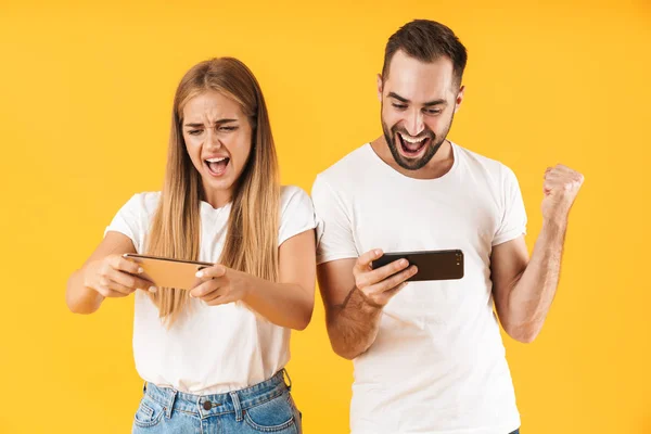 Imagen de pareja emocionada jugando videojuegos en smartphones juntos — Foto de Stock