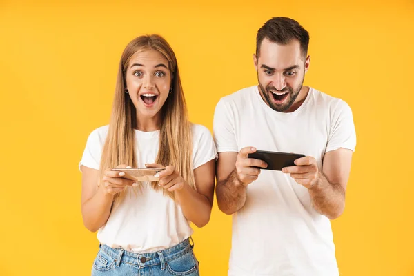 Imagen de pareja complacida jugando videojuegos en smartphones juntos —  Fotos de Stock