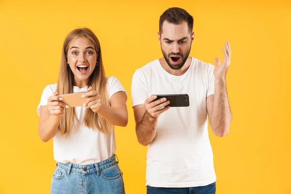 Bild av emotionellt par som spelar video spel på smartphones tillsammans — Stockfoto