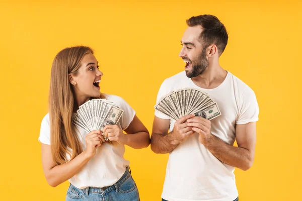 Imagen de feliz pareja regocijándose mientras sostiene un montón de billetes en efectivo — Foto de Stock