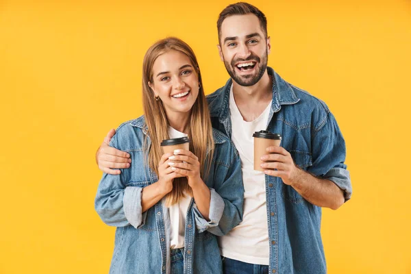 Imagen de pareja encantadora sonriendo mientras sostiene tazas de café para llevar — Foto de Stock