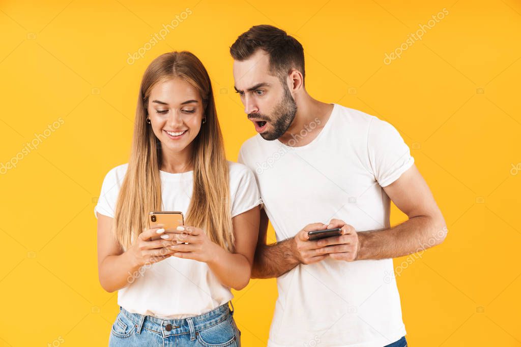 Image of displeased man spying and peeking at cellphone of his girlfriend