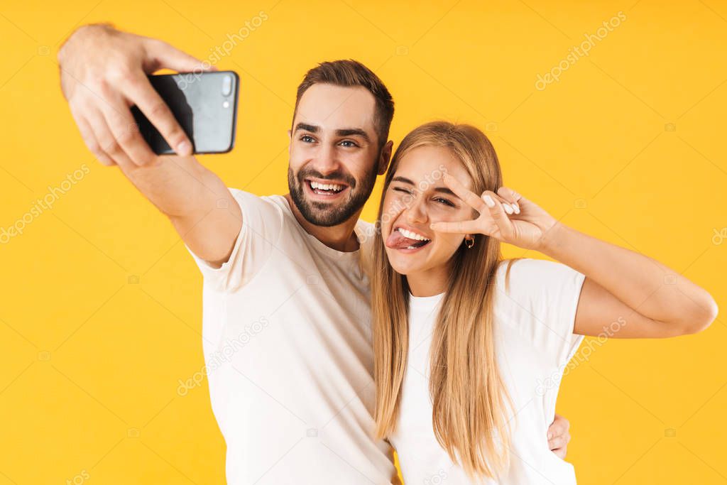 Image of happy couple showing peace sign while taking selfie photo