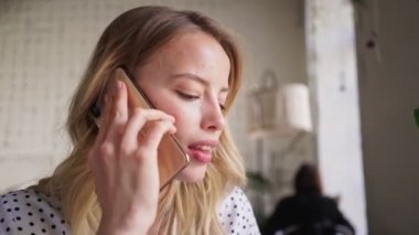 Şirin, sakin, sarışın bir kadının kahve içip, kafede telefonla konuşurken cheesecake yerken görüntüsünü kapatın.