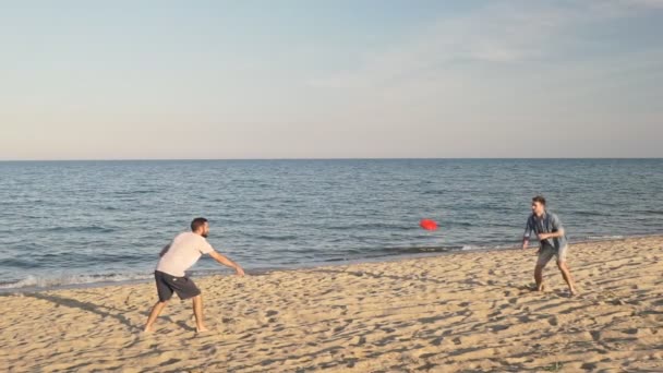 Genç Yakışıklı Adam Deniz Kenarında Eğlenirken Kırmızı Uçan Disk Atıyor — Stok video