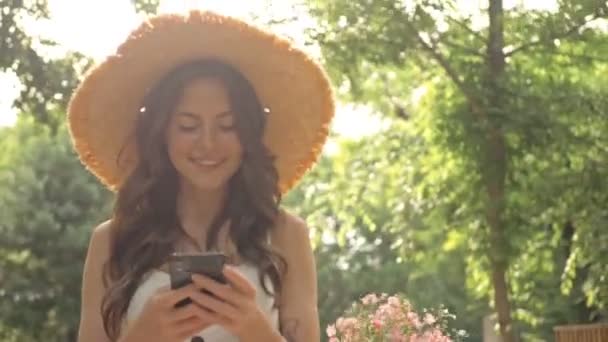 Feliz Jovem Morena Bonita Chapéu Palha Sorrindo Usando Smartphone Enquanto — Vídeo de Stock