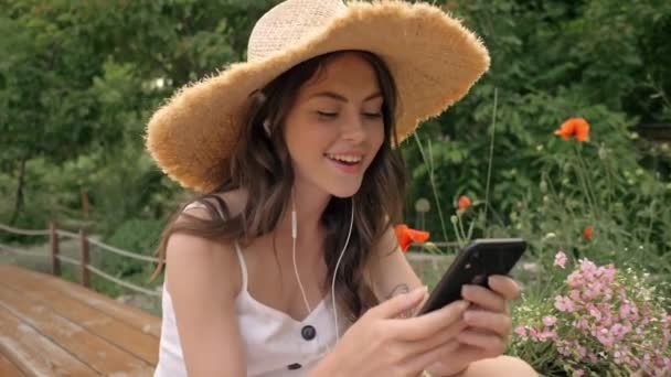 Hasır Şapkalı Hoş Genç Esmer Bir Kadın Kulaklıklı Müzik Dinliyor — Stok video