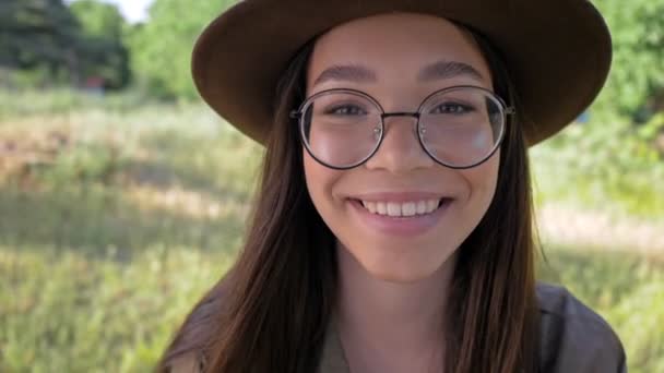 在公园里 你可以看到一个笑容可亲的 可爱的 戴着褐色帽子的年轻黑发女子 她的头发是手工扎成的 — 图库视频影像