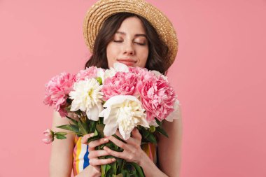 Mutlu neşeli gülümseyen genç sevimli kadın pembe duvar arka plan üzerinde çiçekler tutarak izole poz.