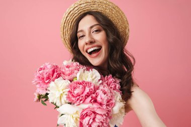Mutlu neşeli gülümseyen genç sevimli kadın pembe duvar arka plan üzerinde çiçekler tutarak izole poz.