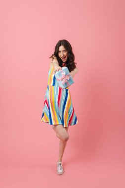 Oldukça neşeli gülümseyen pozitif sevimli kadın pembe duvar arka plan üzerinde mevcut hediye kutusu tutarak izole poz.