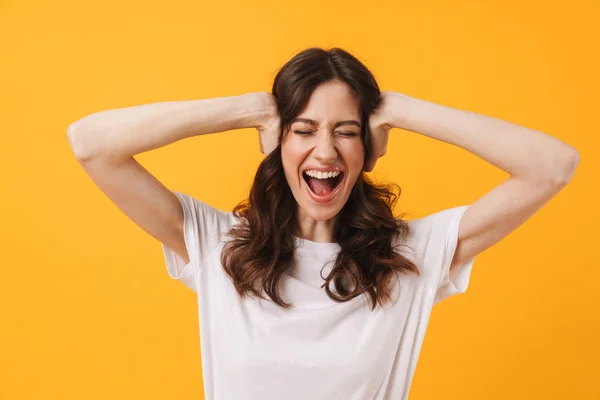 Emotional screaming young woman posing isolated over yellow wall background. — Stockfoto
