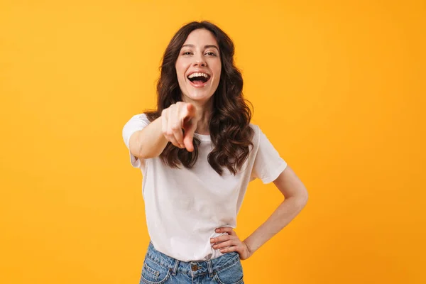 Jovencita riendo alegremente posando aislada sobre el fondo amarillo de la pared señalándote . —  Fotos de Stock