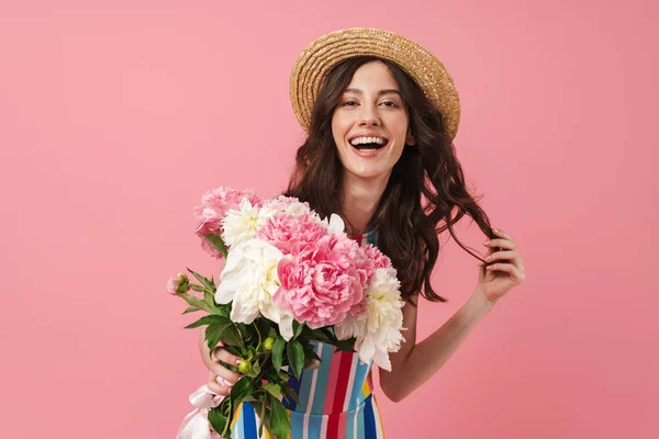 Feliz alegre sorrindo jovem bonito mulher posando isolado sobre rosa parede fundo segurando flores . — Fotografia de Stock