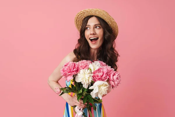 Feliz alegre sonriente joven linda mujer posando aislado sobre fondo de pared rosa sosteniendo flores . — Foto de Stock