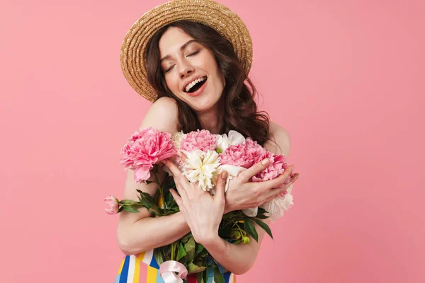 Šťastná Veselě usměvavá ženská roztomilá žena, která se izolovaná přes růžovou zeď držící květiny. — Stock fotografie